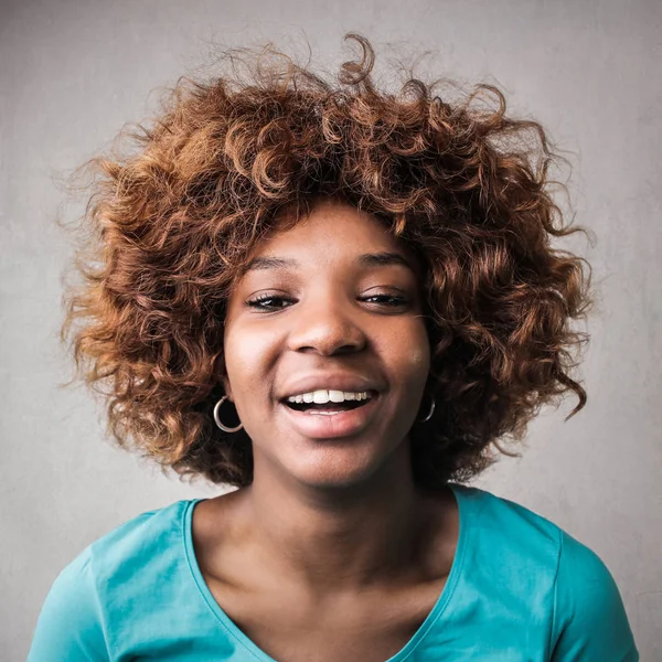 Young Afro woman smiling positively into the camera.