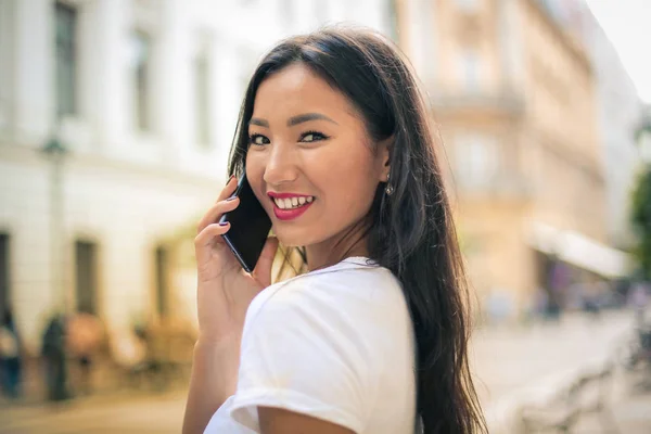 美丽的亚洲妇女谈论智能手机和微笑 — 图库照片