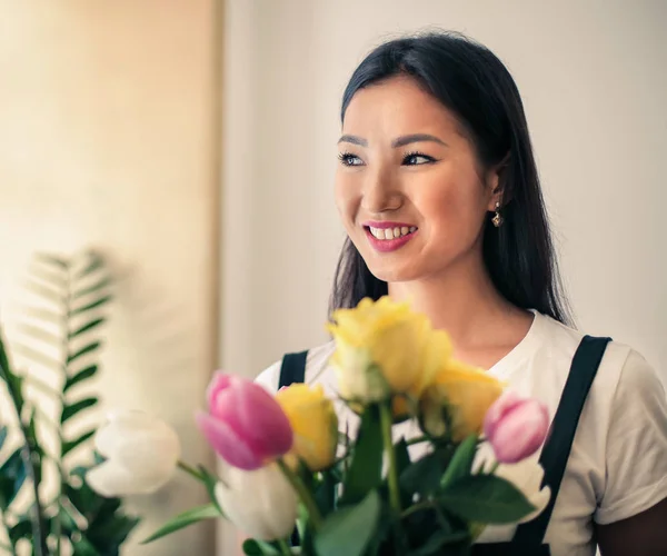 Beautiful Asian woman with flowers smiling positively.