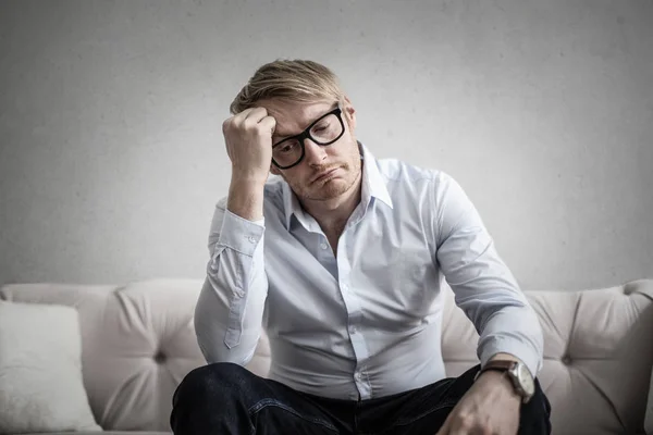 Ung Blond Man Med Glasögon Sitter Soffa Och Har Problem — Stockfoto