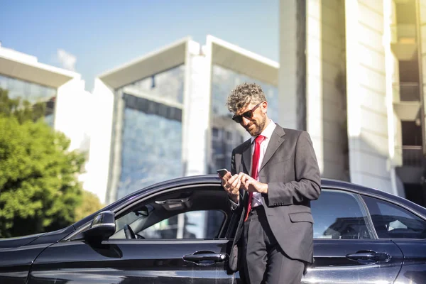 Lockenkopf Lächelt Und Steht Neben Seinem Auto Während Sein Smartphone — Stockfoto