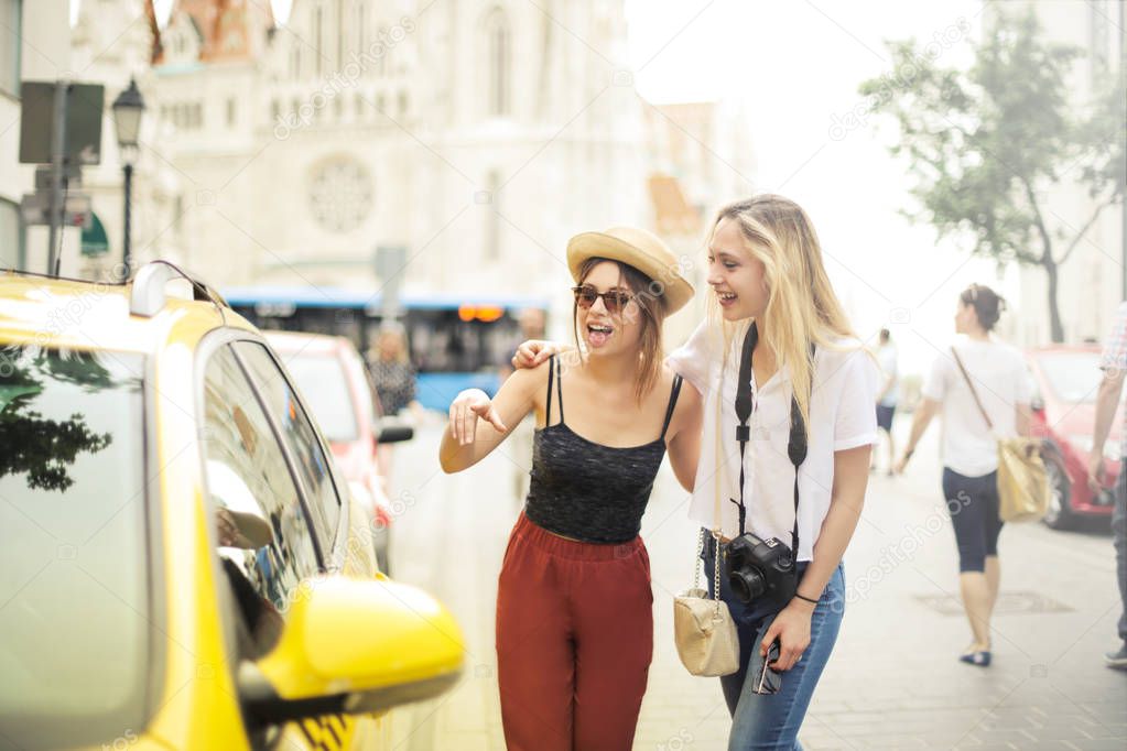 Two young female friends taking a cab on a vacation.