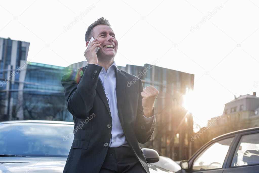 Businessman happily talking on his smartphone and smiling.