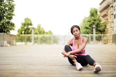 Genç güzel Afro bir kadın oturuyor ve açık rahatlatıcı fitness kıyafeti.