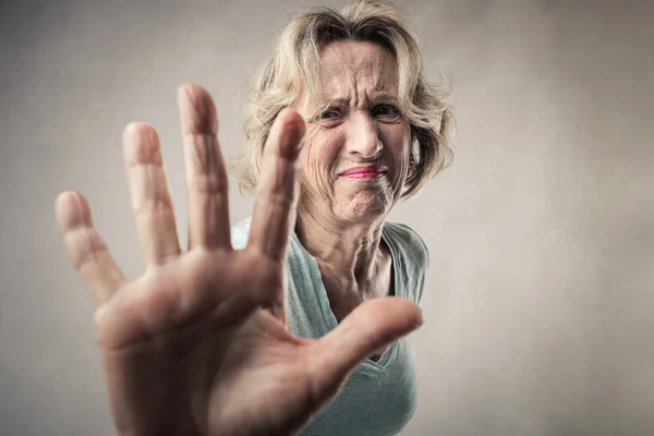 Senior woman showing her palm as refusing or denying.