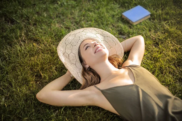 晴れた日に公園の芝生で横になっている麦わら帽子と若いティーンエイ ジャー — ストック写真