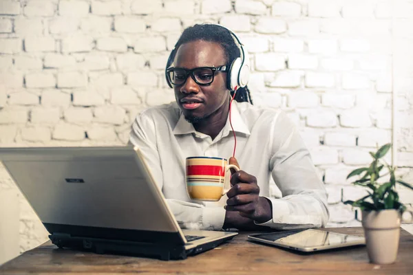 年轻的非洲商人在衬衫与咖啡工作在他的笔记本电脑 — 图库照片