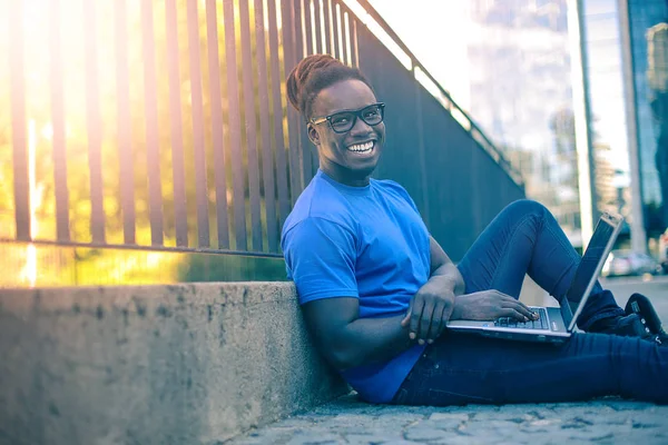 Joven Afro Hombre Sentado Calle Sonriendo Navegando Internet Computadora Portátil — Foto de Stock