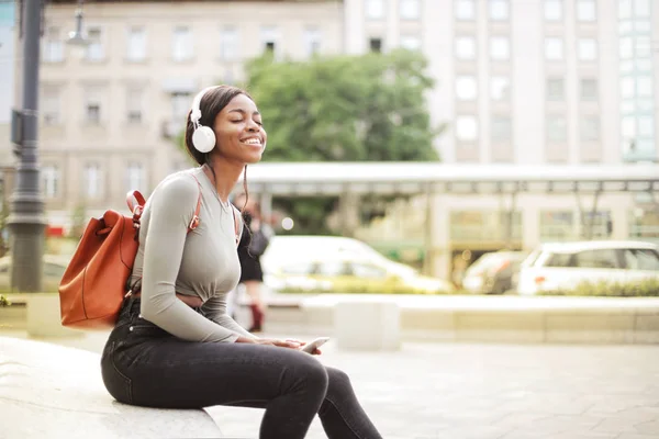 Młoda Piękna Kobieta Afro Słuchawek Plecak Siedzi Relaksując Się Ulicy — Zdjęcie stockowe