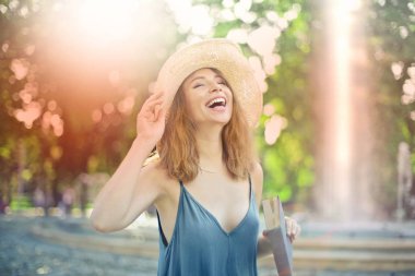 Güneşli bir günde bir parkta gülüyor hasır şapka ile genç güzel kadın.