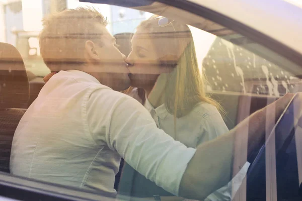 Young couple kissing in the car on a sunny day.