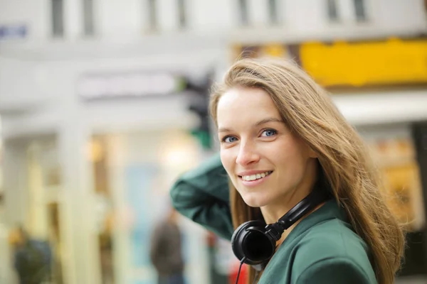 Young confident woman with camera walking in the city and smiling.