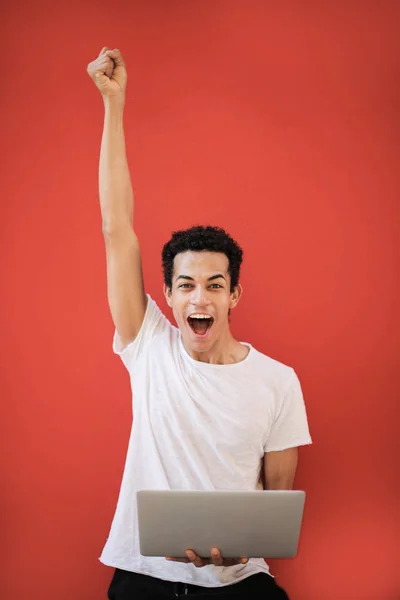 Joven Afro Hombre Con Portátil Animando Celebrando Delante Fondo Rojo — Foto de Stock