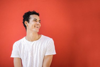 Kıvırcık saçlı genç Afro adam pozlar güvenle ve gülümseyen.