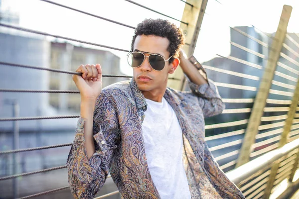 Şehrin modern bir köprü üzerinde poz gözlüklü genç şık Afro adam.