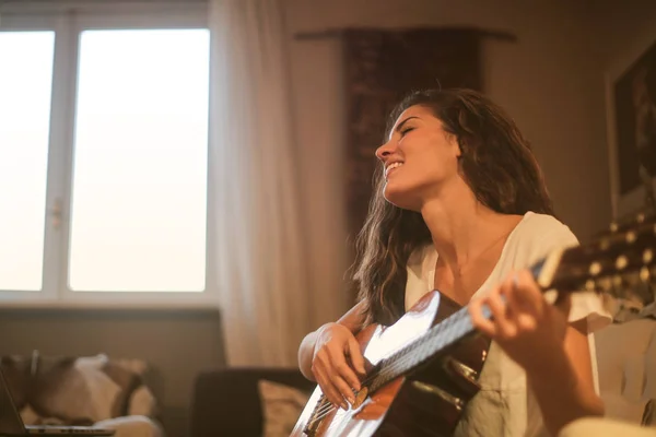 여자는 소파에 앉아서 집에서 기타를 — 스톡 사진