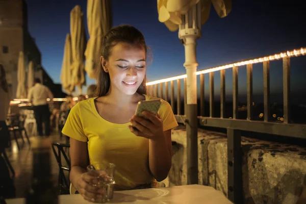 Young Woman Sitting Restaurant Terrace Night Checking Her Smartphone — Stock Photo, Image