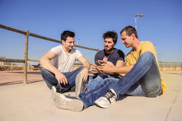 Group Friends Sitting Bridge Sunny Day Checking Smartphone — Stock Photo, Image