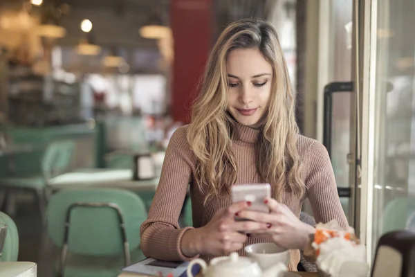 Junge Blonde Frau Sitzt Einem Tisch Und Checkt Ihr Smartphone — Stockfoto