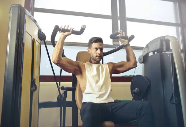 Hombre Atlético Joven Haciendo Ejercicios Gimnasio Una Máquina Prensa Hombro —  Fotos de Stock