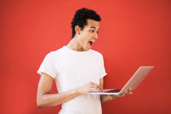 Young Afro man checking his computer and astonished.