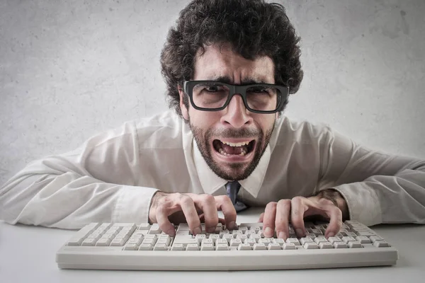 Genç adam kıvırcık saçlı ve gözlük çok korkmuş ve umutsuzca onun klavyede yazarak.