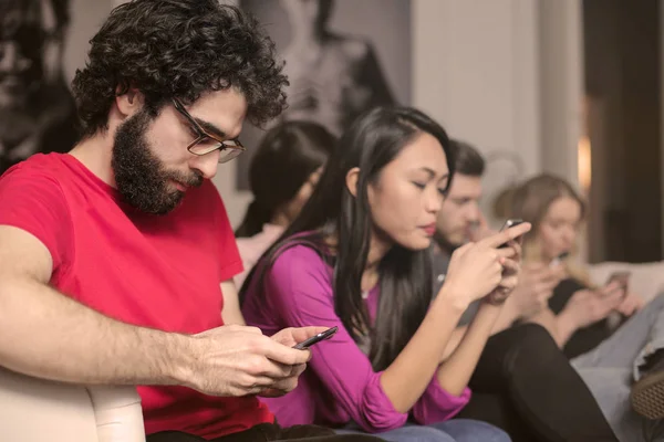 Grupo Amigos Sentados Sofá Revisando Sus Teléfonos Inteligentes —  Fotos de Stock