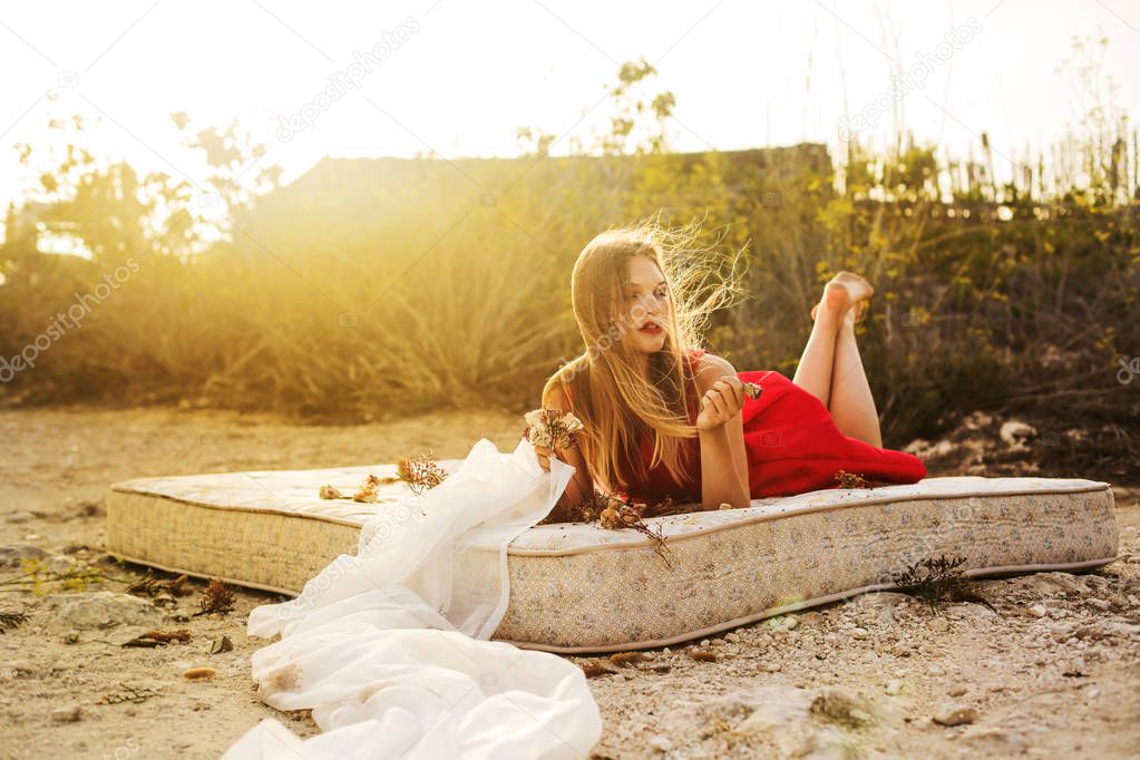 Young beautiful woman lying on a mattress on a sunny summer day.