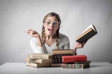 Bir fikir olan kitaplarla onun masasında gözlüklü genç sarışın öğrenci.