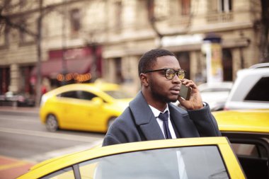 Taksiyle ve kentin bir smartphone cep telefonu ile konuşurken siyah işadamı.