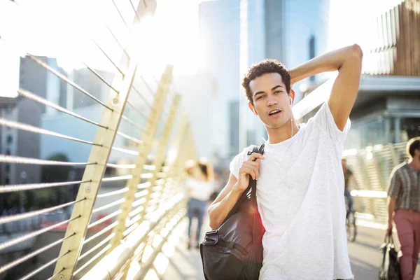 Genç, kendine güvenen, sportif adam onun earphones ile yürüyüş şehir.