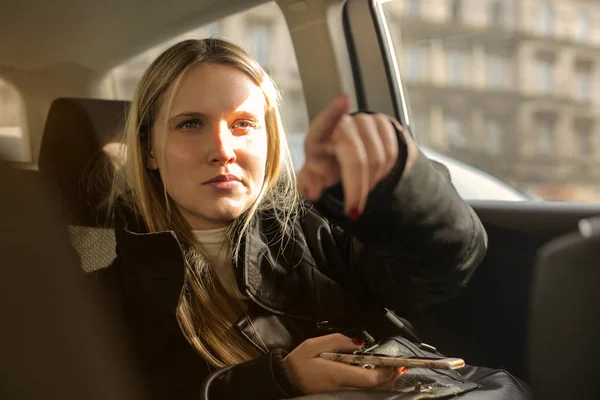 Νεαρή Ξανθιά Γυναίκα Ένα Smartphone Ένα Ταξί Προτεταμένο Δάχτυλο — Φωτογραφία Αρχείου