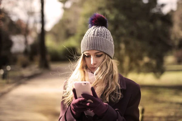 通りで彼女のスマート フォンをチェック冬の少女 — ストック写真