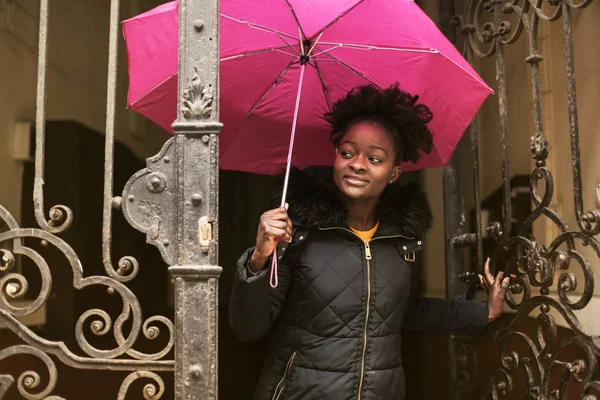 年轻的黑人妇女走出一座旧建筑与她的雨伞 — 图库照片