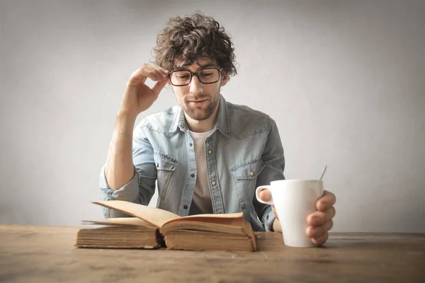 Junger Mann Liest Ein Buch Mit Einer Tasse Kaffee — Stockfoto