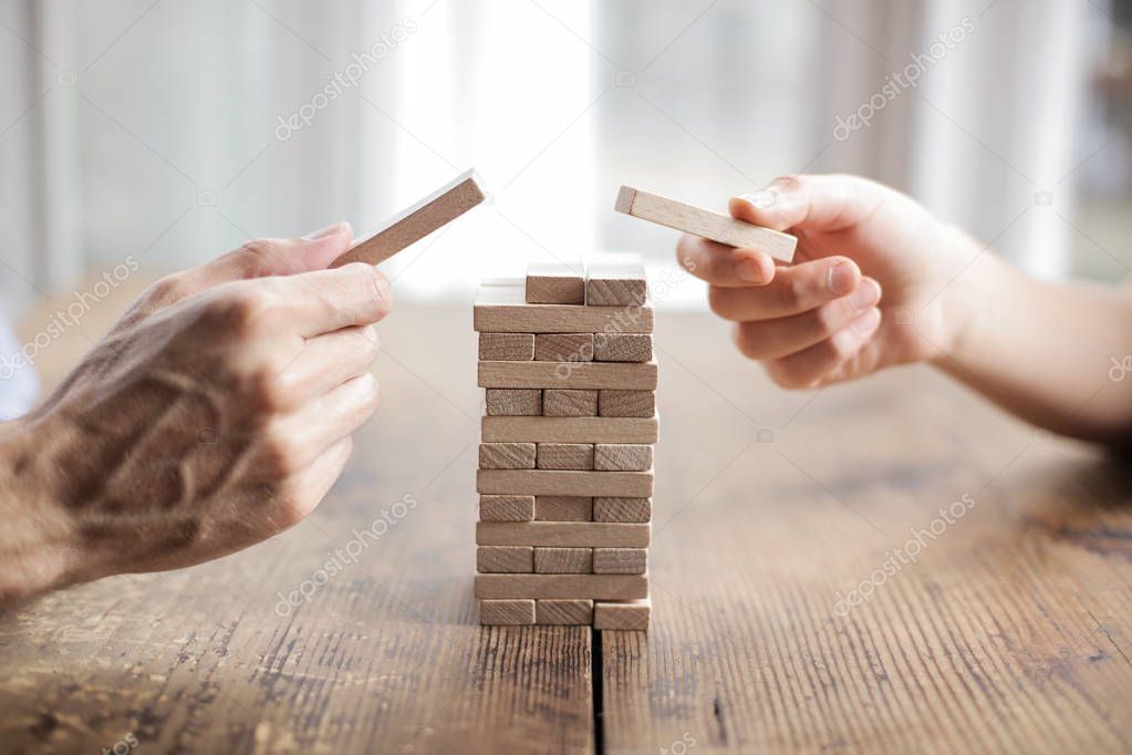 Hands playing with wooden bricks.