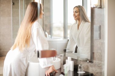 Genç güzel kadın banyoda aynaya bakarak.