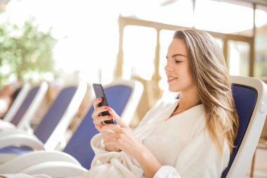 Rahatlatıcı ve onun smartphone kontrol genç güzel kadın.