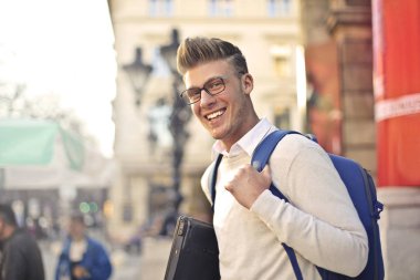 Şehirde gülümseyen genç öğrenci.