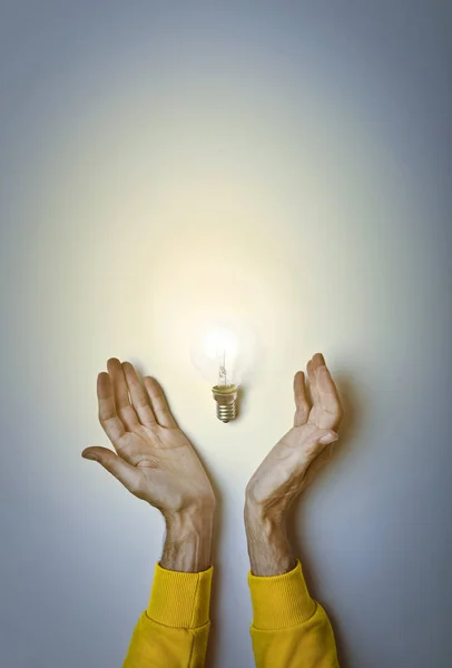 手拿明亮的灯泡在灰色明亮的背景 创造性思维理念 — 图库照片