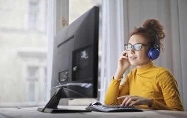 Çalışma ve müzik ekran önünde gözlüklü genç kadın