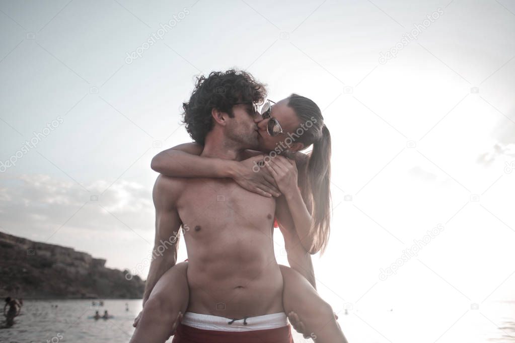 Young beautiful couple holding and embracing each other on the beach