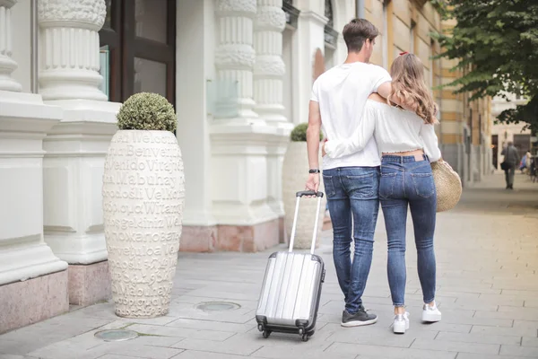 young couple walking in the street with suitcase
