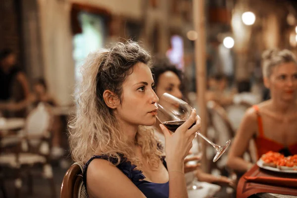 woman drinking wine at a bar with friends