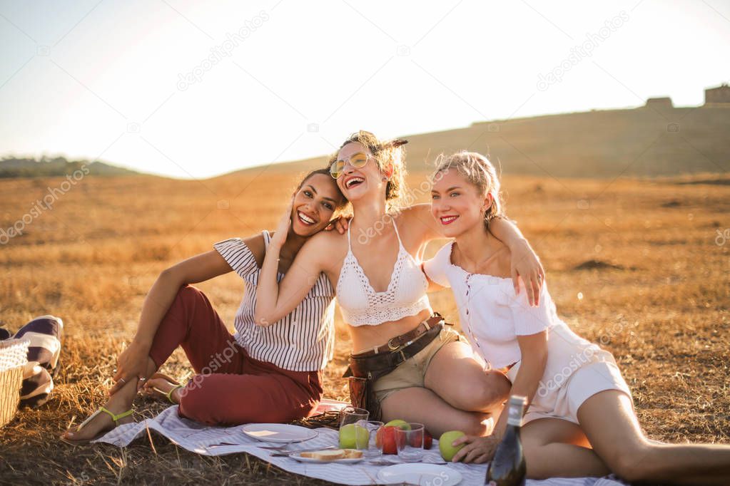 young friends having picnic and enjoying vacation countryside
