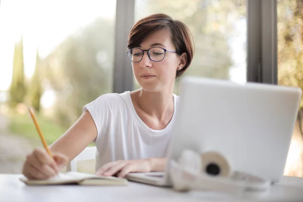 Jovem Mulher Tomando Notas Frente Seu Laptop — Fotografia de Stock