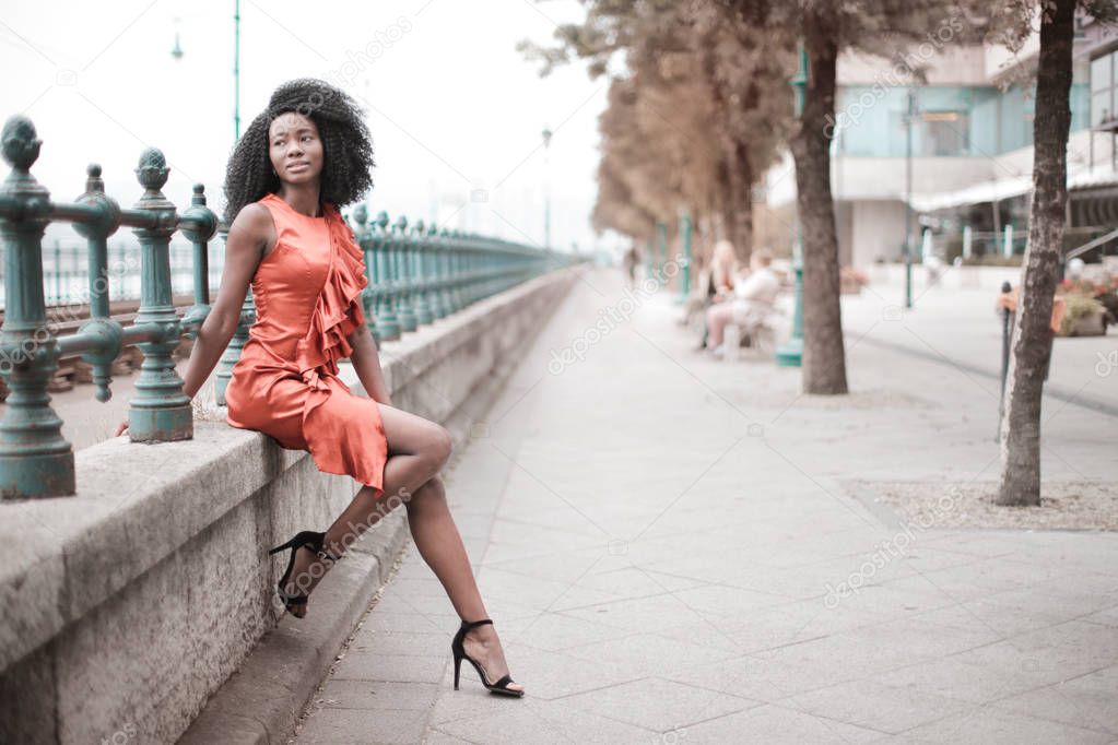 Elegant black girl sitting in the street
