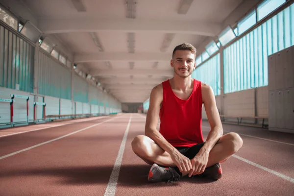 座っていると陸上競技場での肖像画の笑みを浮かべて選手男 — ストック写真