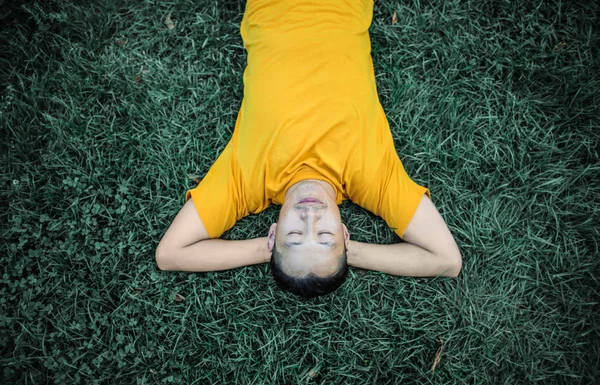 asian young man sleeping on the grass