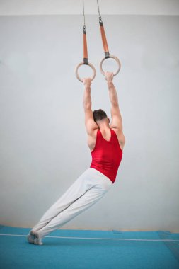 Yüzük holding, atlama ve spor salonunda sanatsal egzersizleri yapıyor genç sporcu adam 